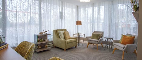 Una sala de estar con un sofá, sillones, una mesita de centro y una estantería.