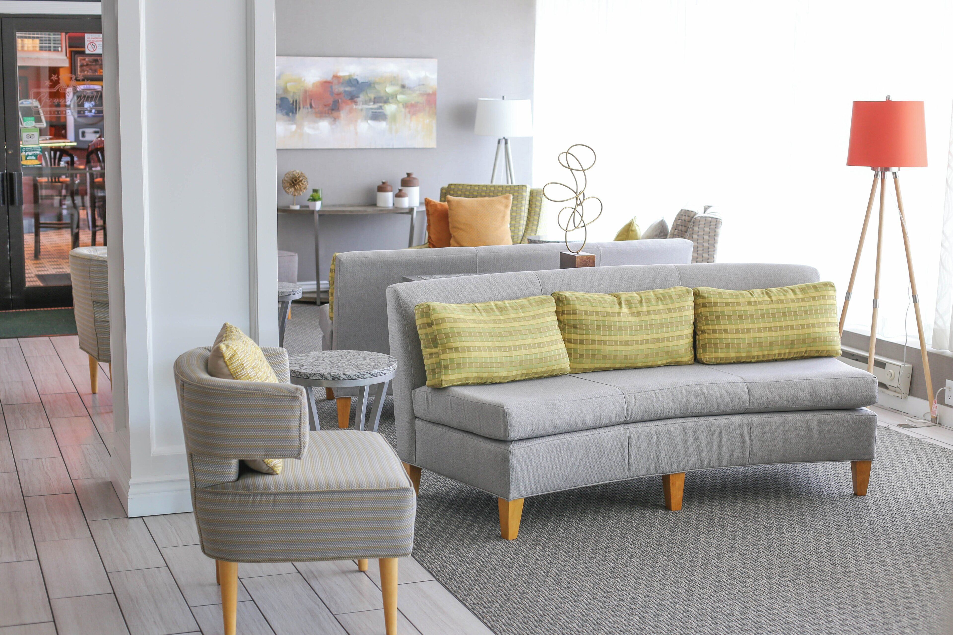 A modern living room with a grey sofa, striped armchair, and a small round table.