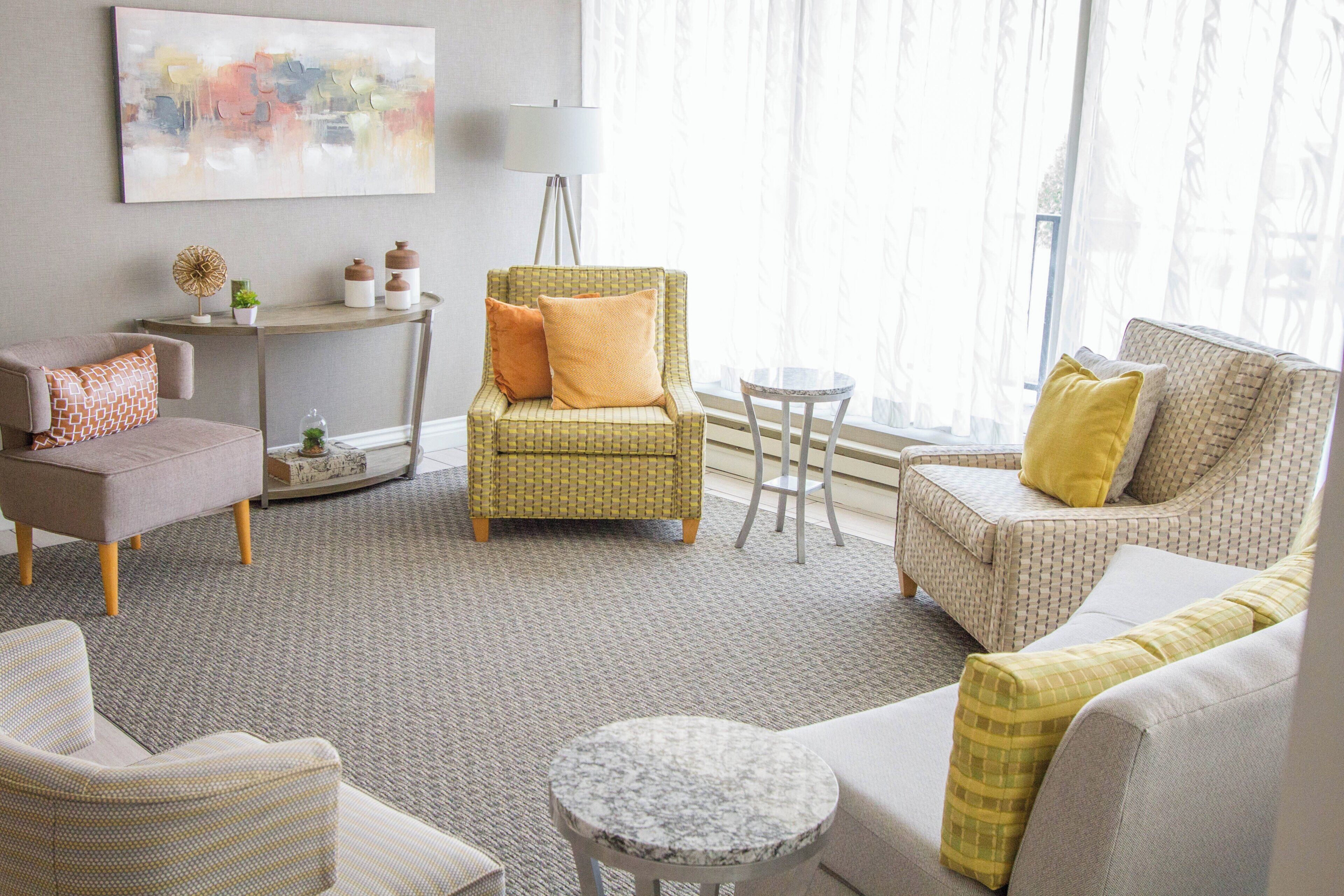 Una sala de estar con sofá, sillón, reposapiés y una mesita redonda.