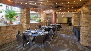 Un restaurant aux murs de briques, aux tables rondes et décoré de guirlandes lumineuses.