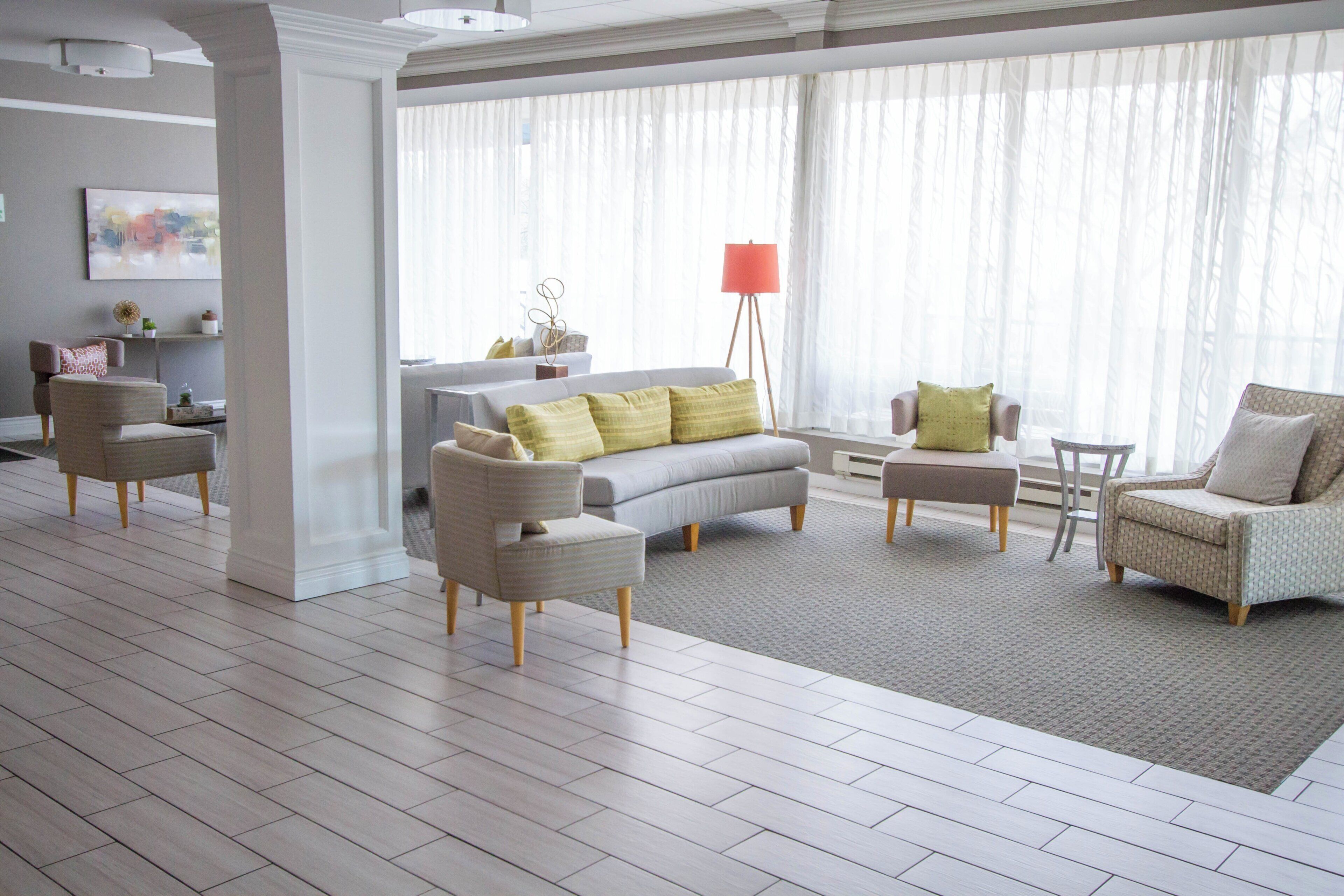 Un salon spacieux avec un canapé gris, deux fauteuils, une table basse et un lampadaire.