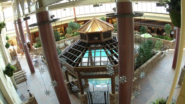 Un atrium à plusieurs niveaux, doté d’une piscine centrale dont le fond est en verre, et entouré de colonnes et de luminaires décoratifs en forme d’étoile.