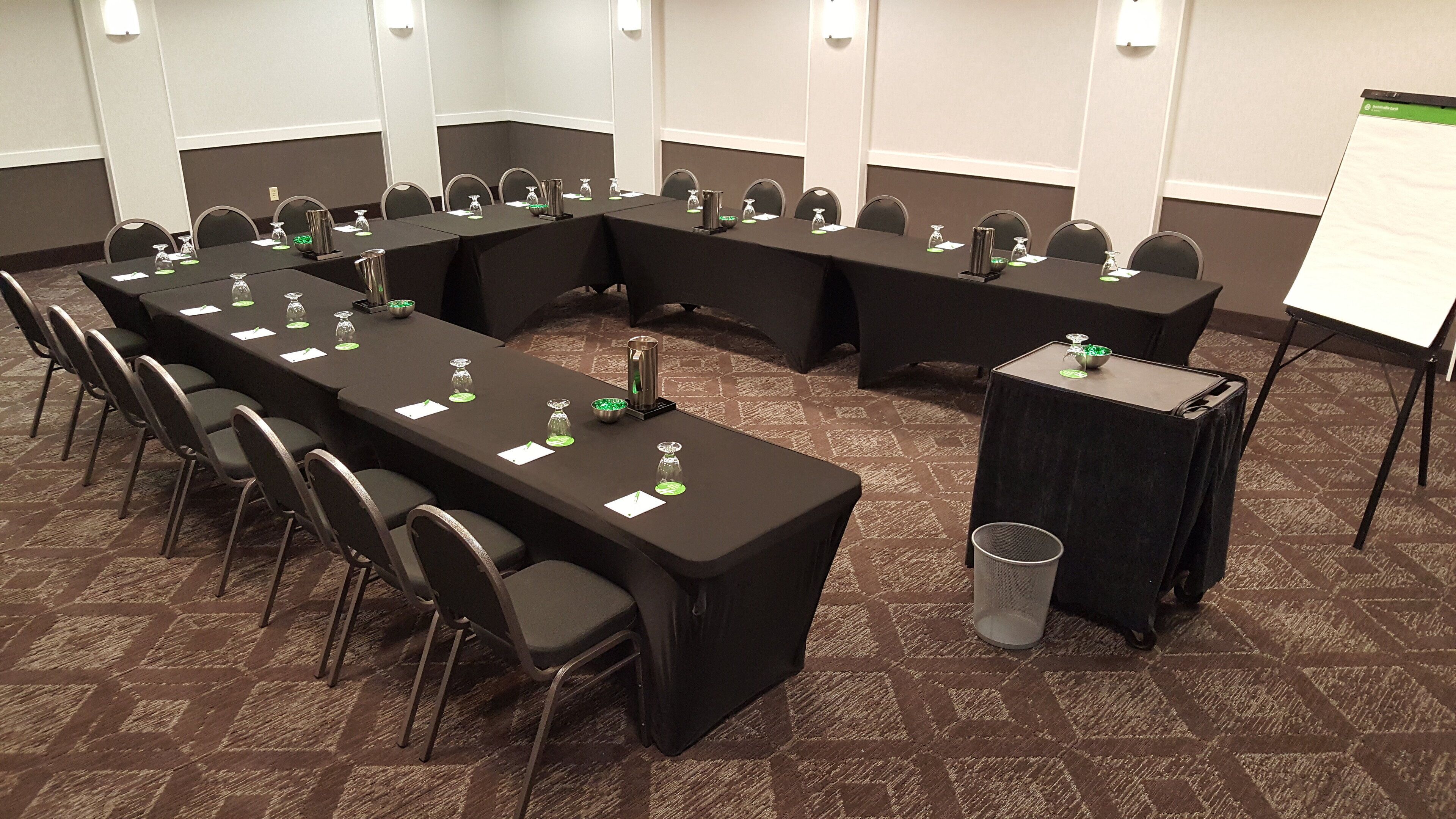 A conference room with long tables, chairs, and a whiteboard.
