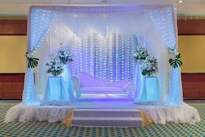 Stunning stage area with a white sofa, floral arrangements, and a patterned carpet.