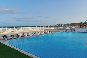 Una piscina al aire libre, sombrillas, sillones reclinables de piscina