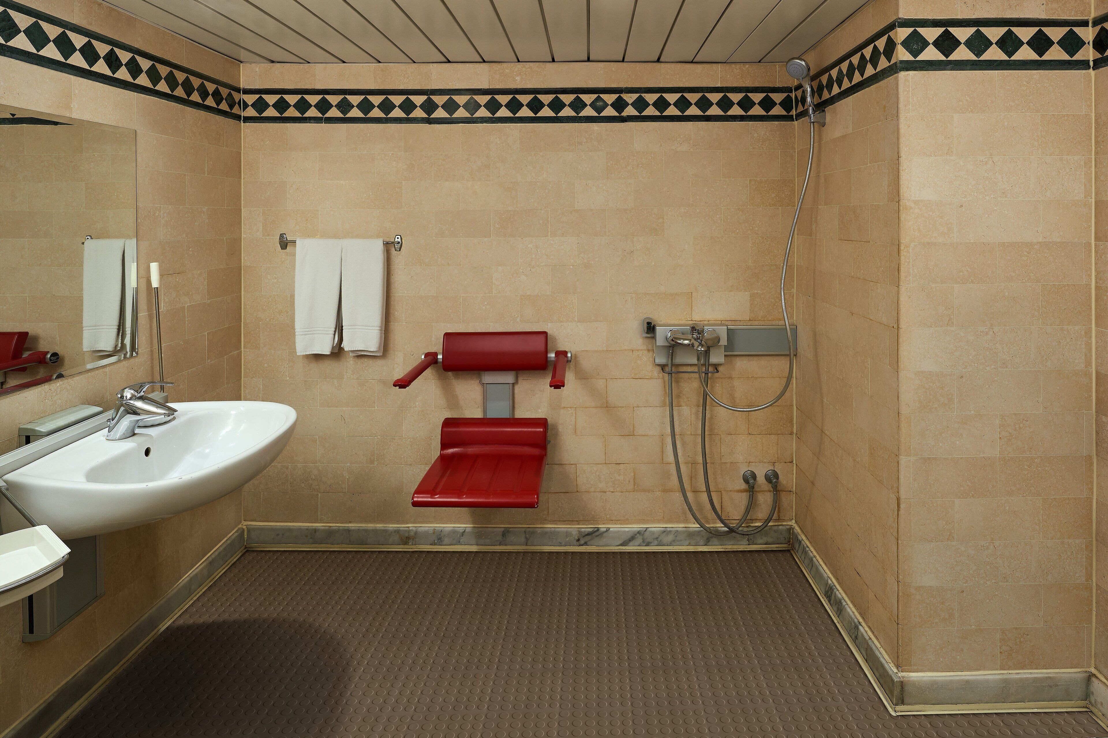 Un baño con lavamanos, espejo, toallero y ducha.