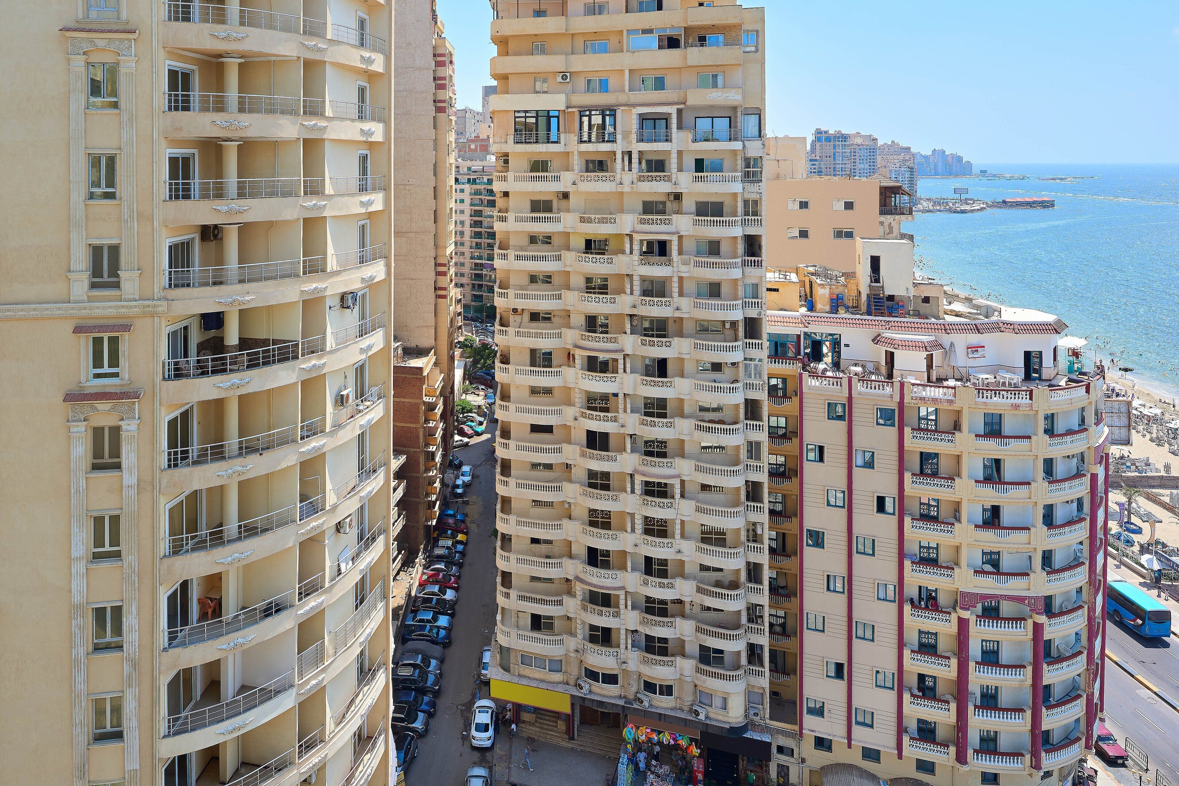 Un hôtel à plusieurs étages, doté de balcons, d’un parking et offrant une vue sur la mer.