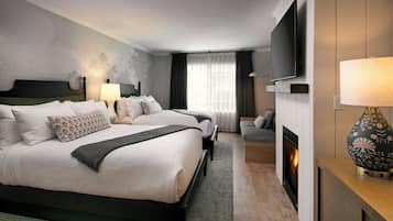 A hotel room with two beds, a TV, a fireplace, and a lamp.