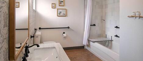 A bathroom with a marble sink, a glass shower enclosure, a towel rack, and framed pictures on the wall.