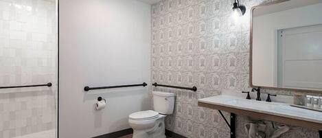 A bathroom with a toilet, a sink with a mirror, and a patterned wall.