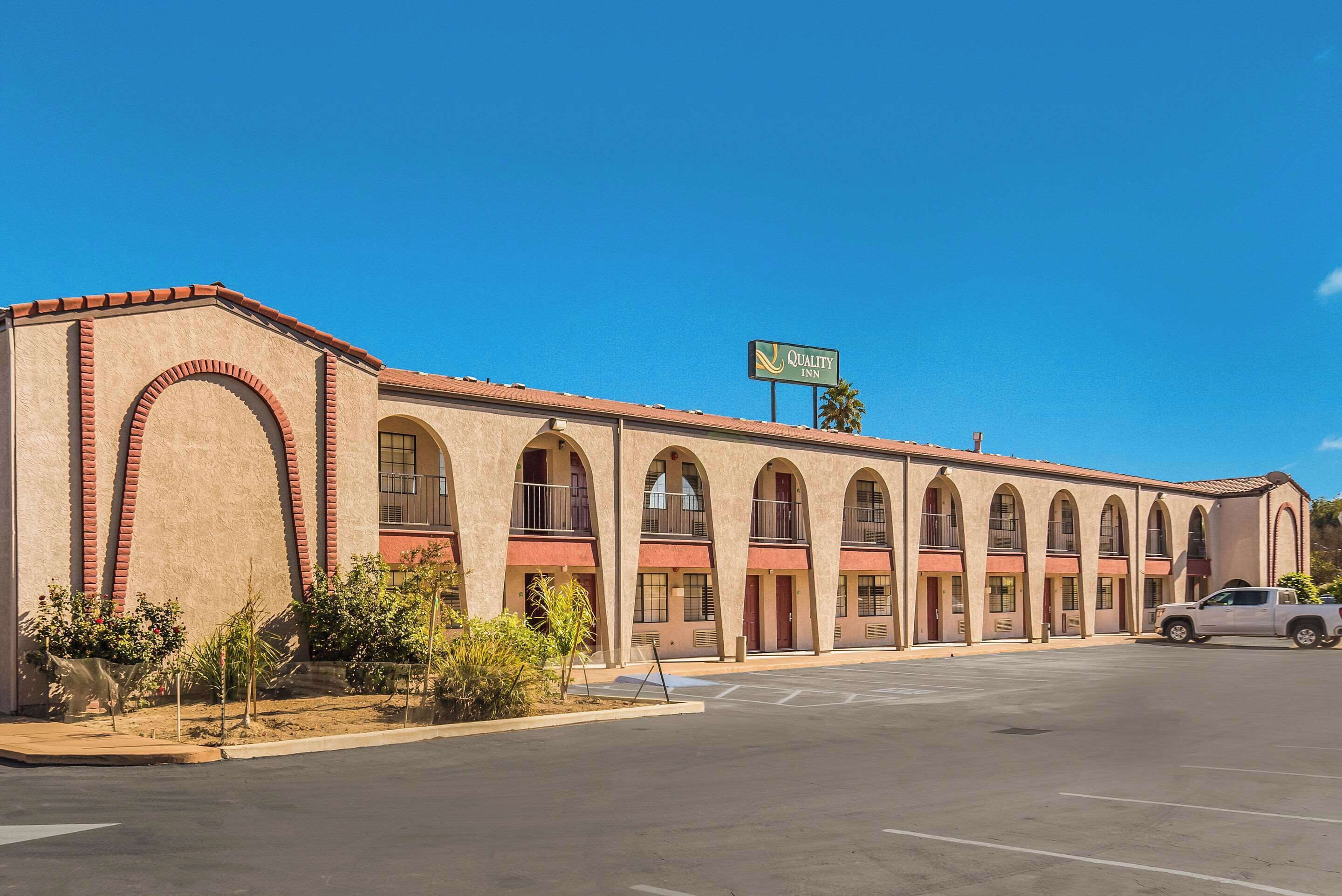 A motel with a row of arched windows and a sign indicating it is a Quality Inn.