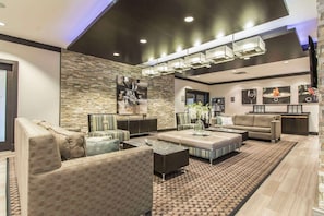 A modern living room with a stone accent wall, a large sectional sofa, a coffee table, and a patterned rug.