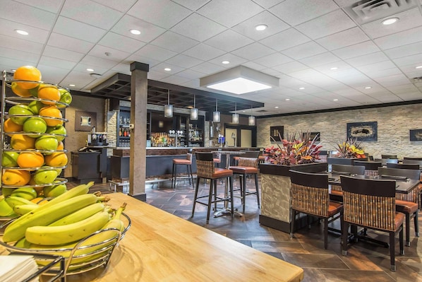 A restaurant with a bar area, seating, and a fruit display. - Quattro Hotel & Conf. Centre, an Ascend Collection Hotel (Sault Ste. Marie)