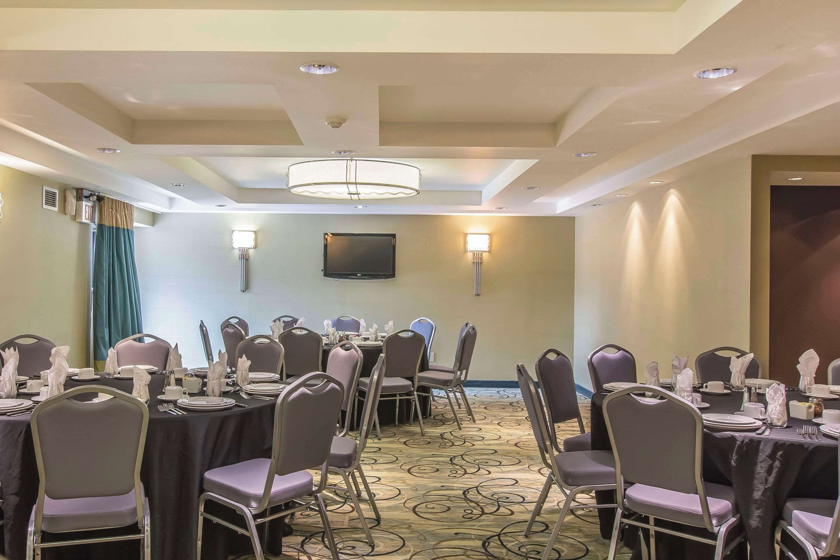 A conference room with round tables, chairs, and a television on the wall.