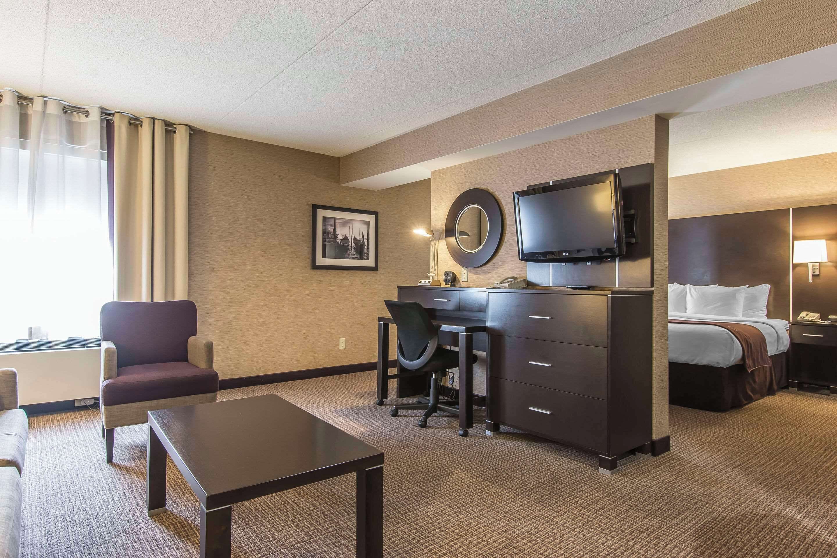 A hotel room with a desk, chair, bed, and a television.