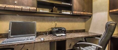 Un espacio de trabajo en un hotel con una computadora de escritorio, una impresora y dos sillas de oficina.