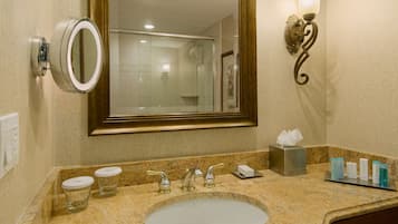 A bathroom with a sink, mirror, and shower.