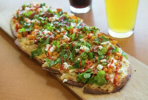 Una pizza larga y delgada con diversos ingredientes sobre una tabla de madera.