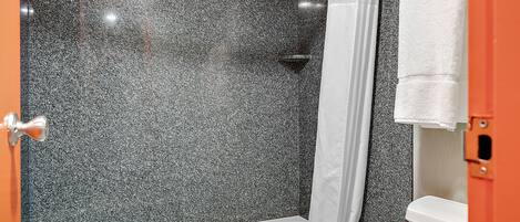 A bathroom with a shower, toilet, and bathtub.