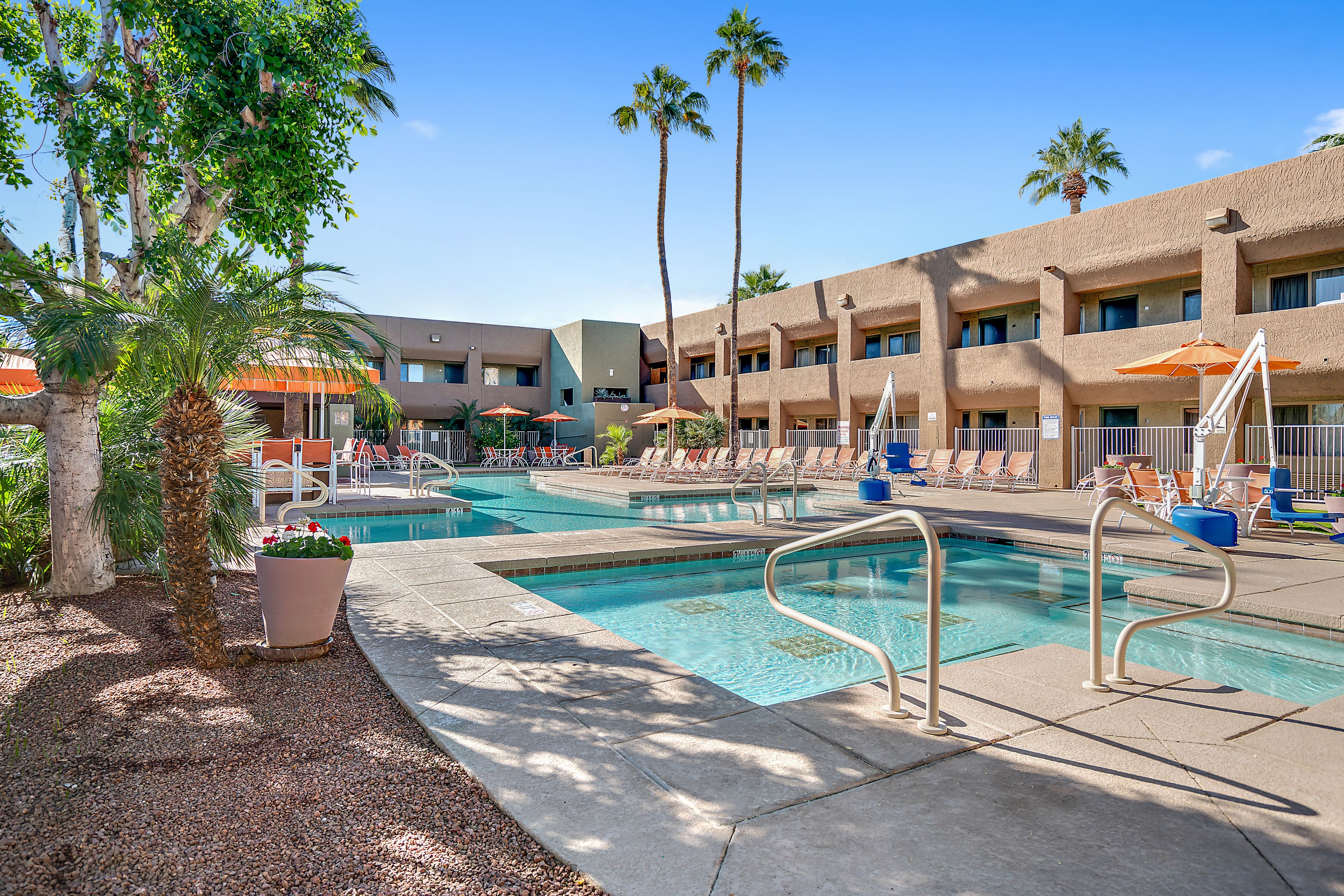 A pool area with multiple swimming pools, lounge chairs, and palm trees.