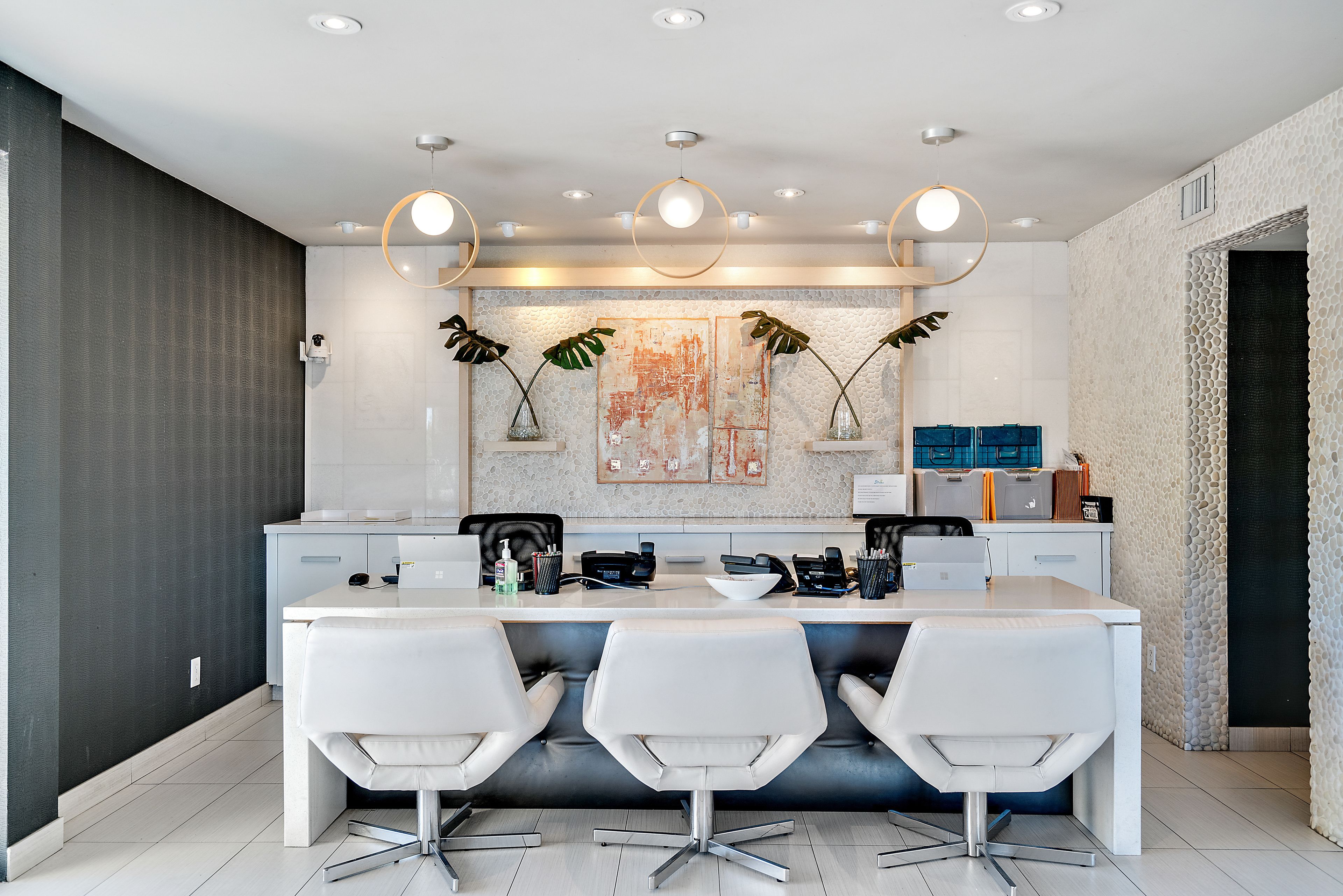 A modern kitchen with a central island, white chairs, and pendant lighting.