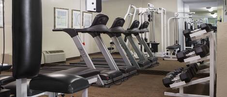 A gym with treadmills, weight machines, and dumbbells.