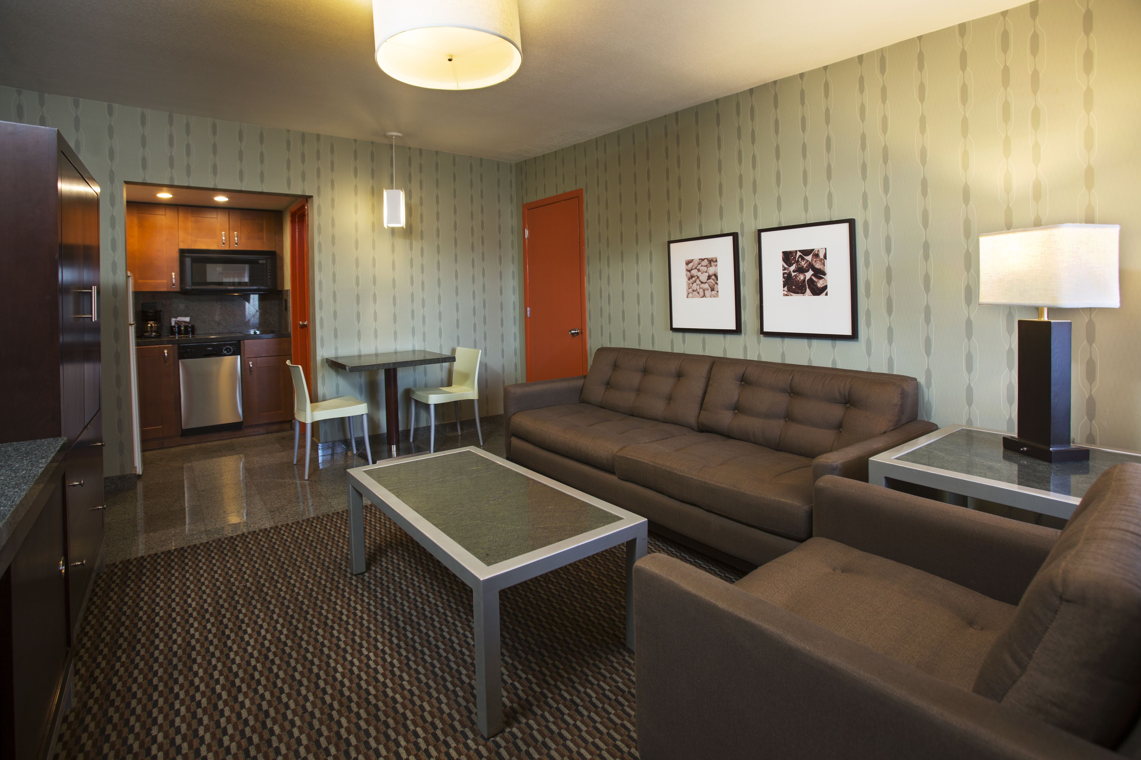 Una habitación de hotel compacta con kitchenette, un sofá, una mesita de centro y un comedor.