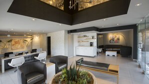 Un vestíbulo moderno con mostrador de recepción, zona de estar y cocina al fondo.