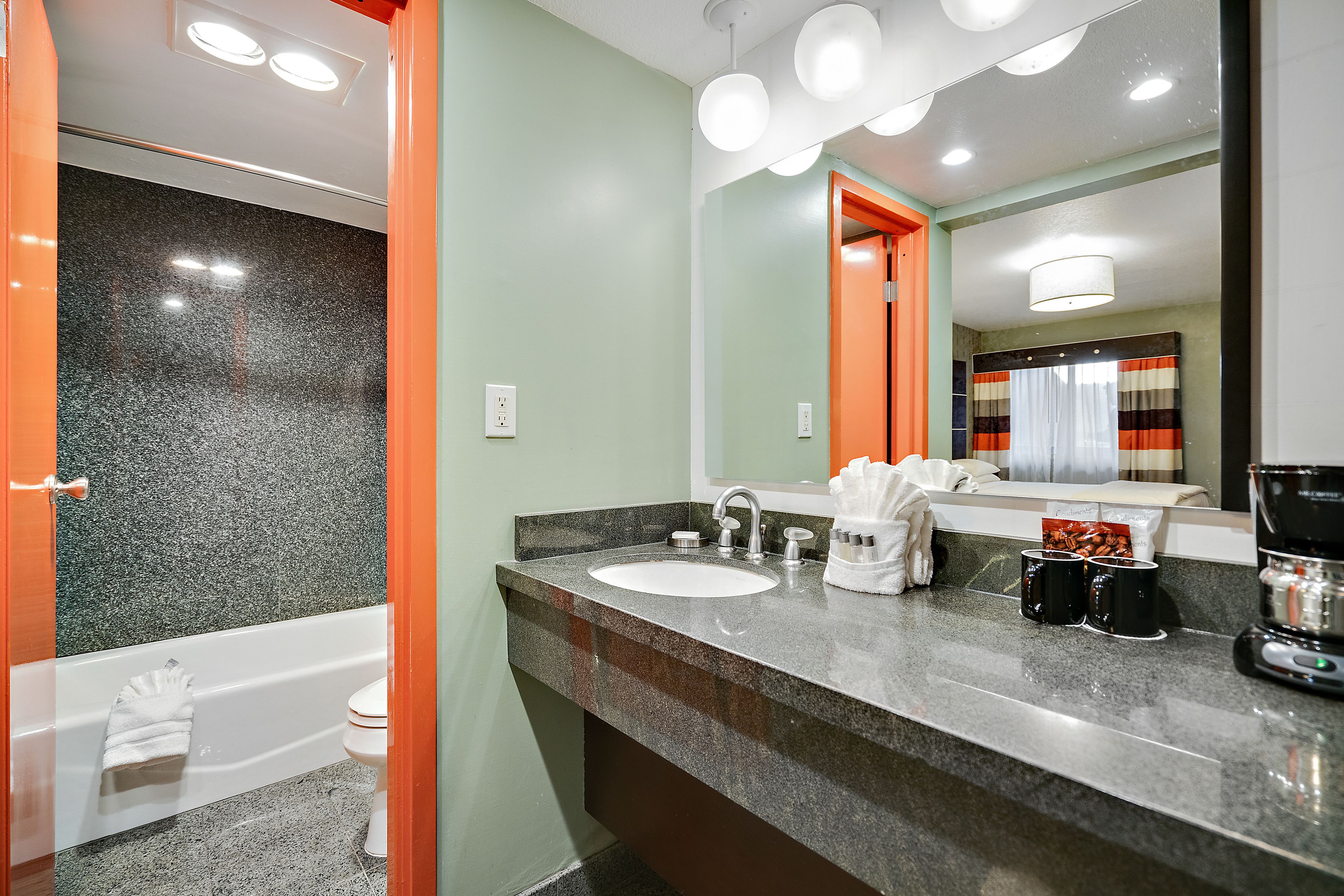 Une salle de bain moderne avec un comptoir en granit, un lavabo blanc et un porte-serviettes apparent.