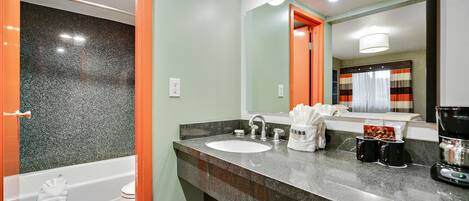 Une salle de bain moderne avec un comptoir en granit, un lavabo blanc et un porte-serviettes apparent.