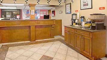 A hotel lobby with a reception desk, a coffee station, and a framed picture on the wall.