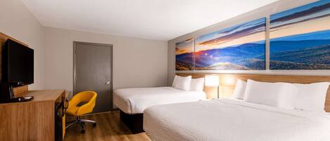 Habitación de hotel con dos camas, un escritorio con silla, televisor y un cuadro de un paisaje al atardecer.