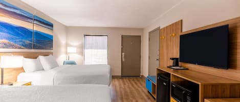A hotel room with two beds, a TV, a desk, and a painting on the wall.