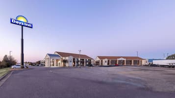 A Days Inn with a large parking lot and a building with a brown roof.