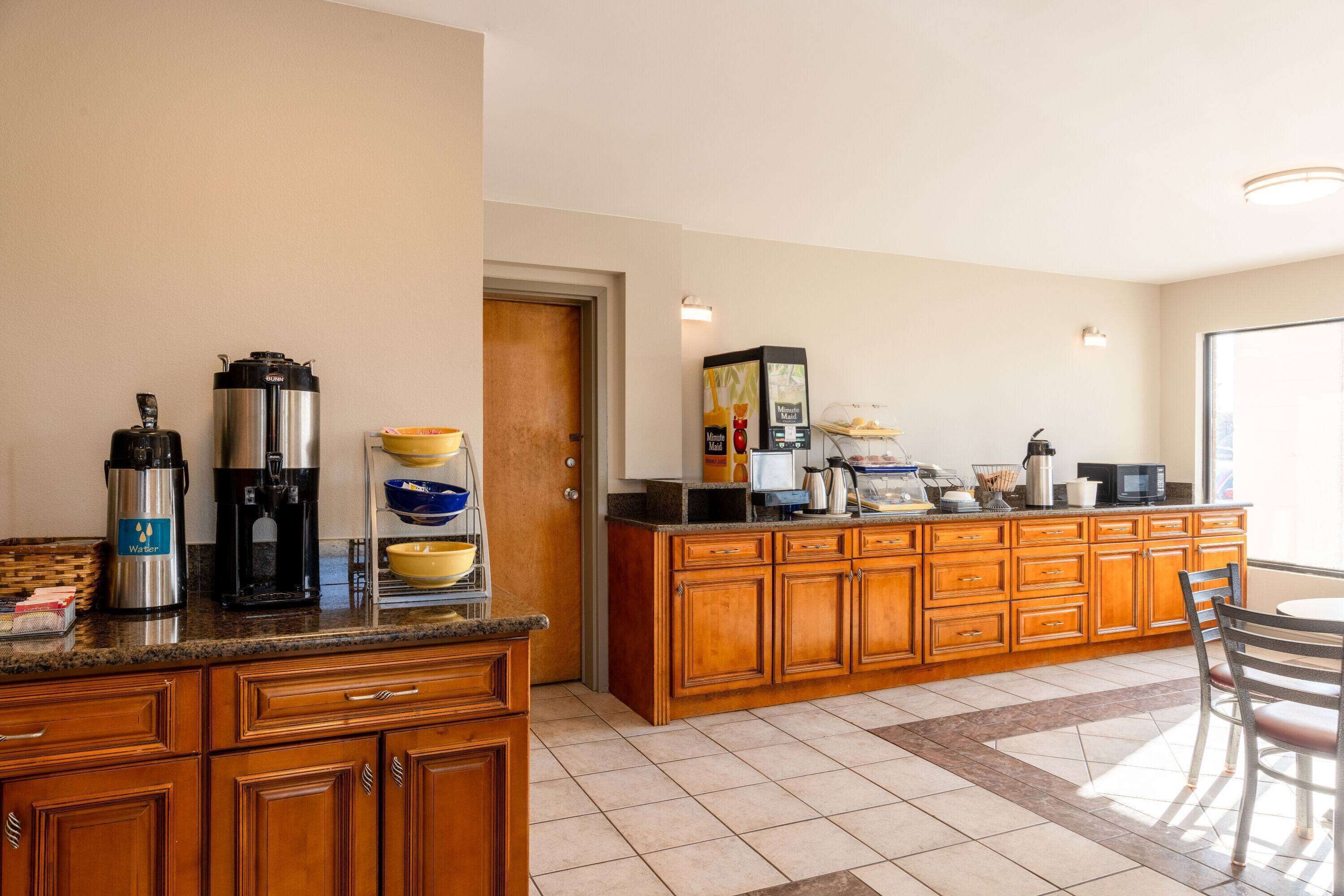A kitchen with wooden cabinets, a granite countertop, a coffee maker, a toaster, and a microwave.