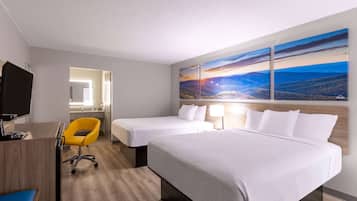 A hotel room with two beds, a desk with a chair, a TV, and a large landscape painting on the wall.