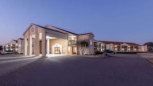 Un hôtel à plusieurs étages doté d’une entrée principale, de nombreux balcons et d’un parking.