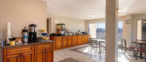Una cocina amplia con armarios de madera, una zona de café y un comedor con sillas y una mesa.