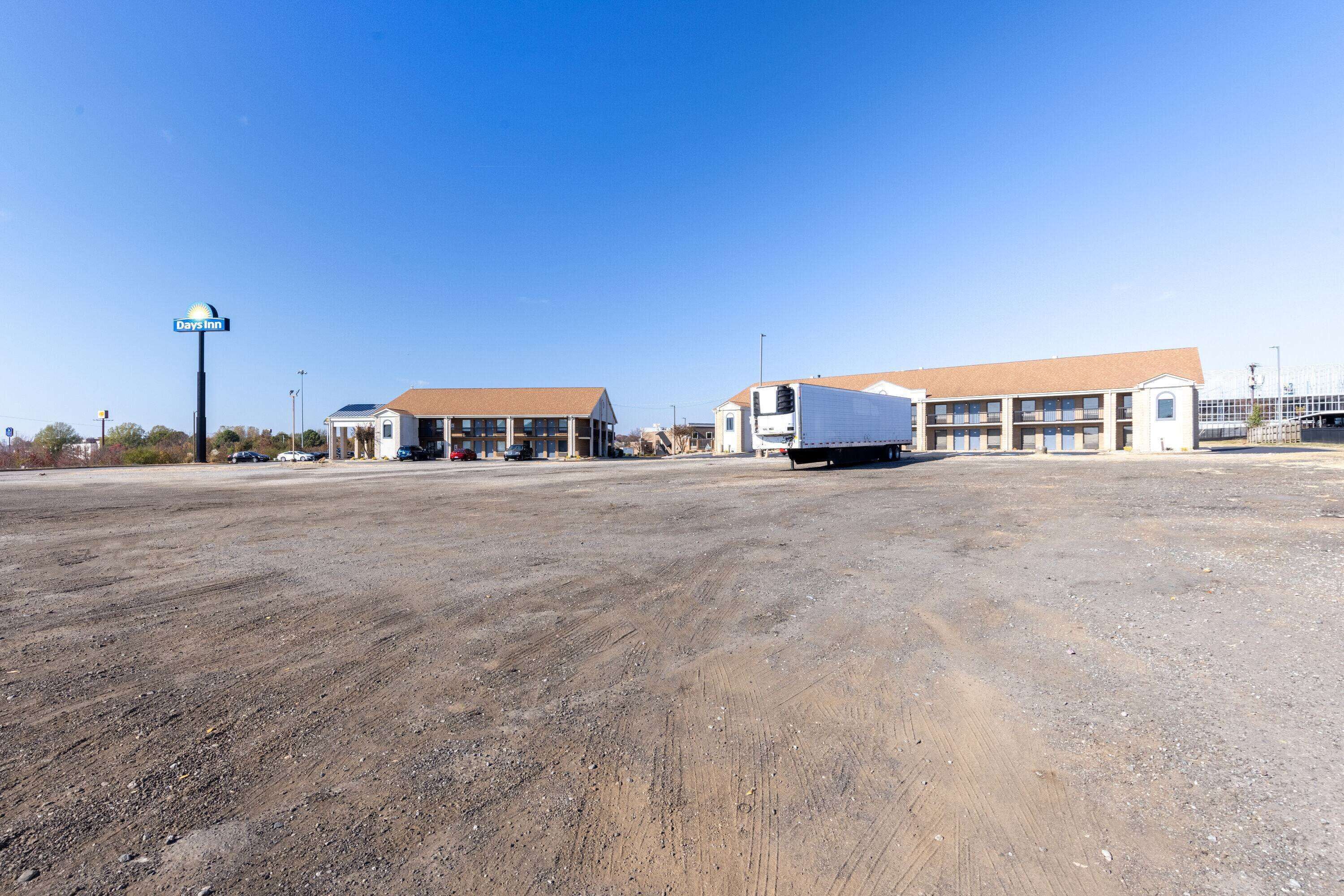 A Days Inn with a large parking lot and a building with a brown roof.