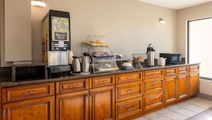 Une cuisine avec des meubles de rangement en bois, une machine à café, un four à micro-ondes et un grille-pain.