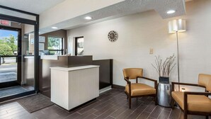 A reception area with a reception desk, two leather chairs, a clock, and a lamp.