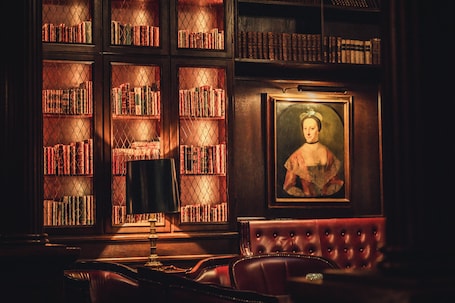 A library with bookshelves, a framed portrait, and leather furniture.. ProfilHotels Copenhagen Plaza