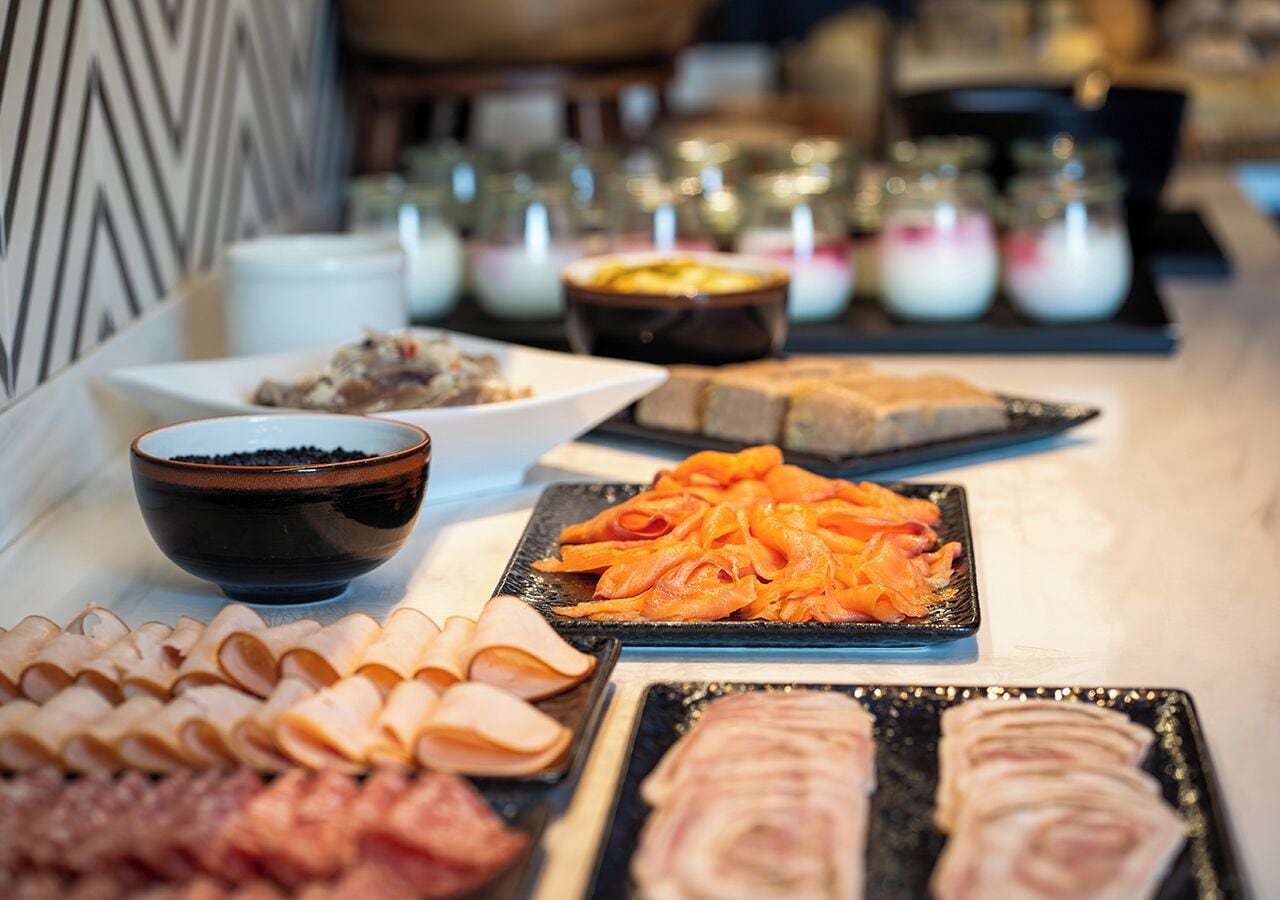 A buffet with various food items including sliced meats and seafood.