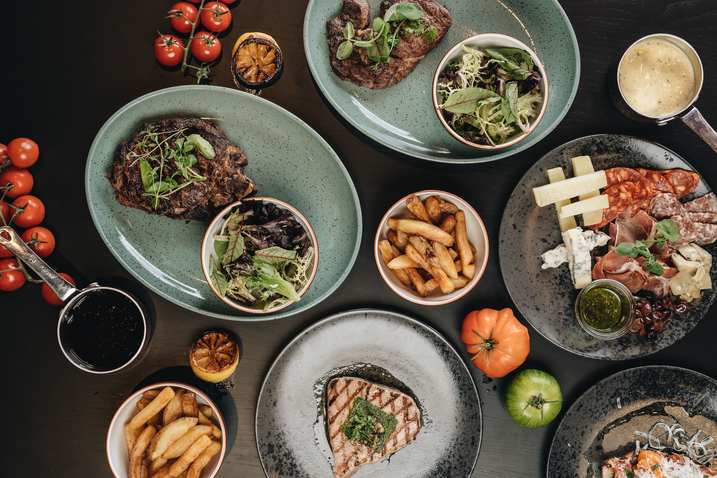 A variety of dishes including steak, fries, and cheese on plates.
