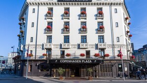 Un hotel de varios pisos con un estilo arquitectónico clásico, que cuenta con balcones con jardineras y un letrero destacado del Copenhagen Plaza.