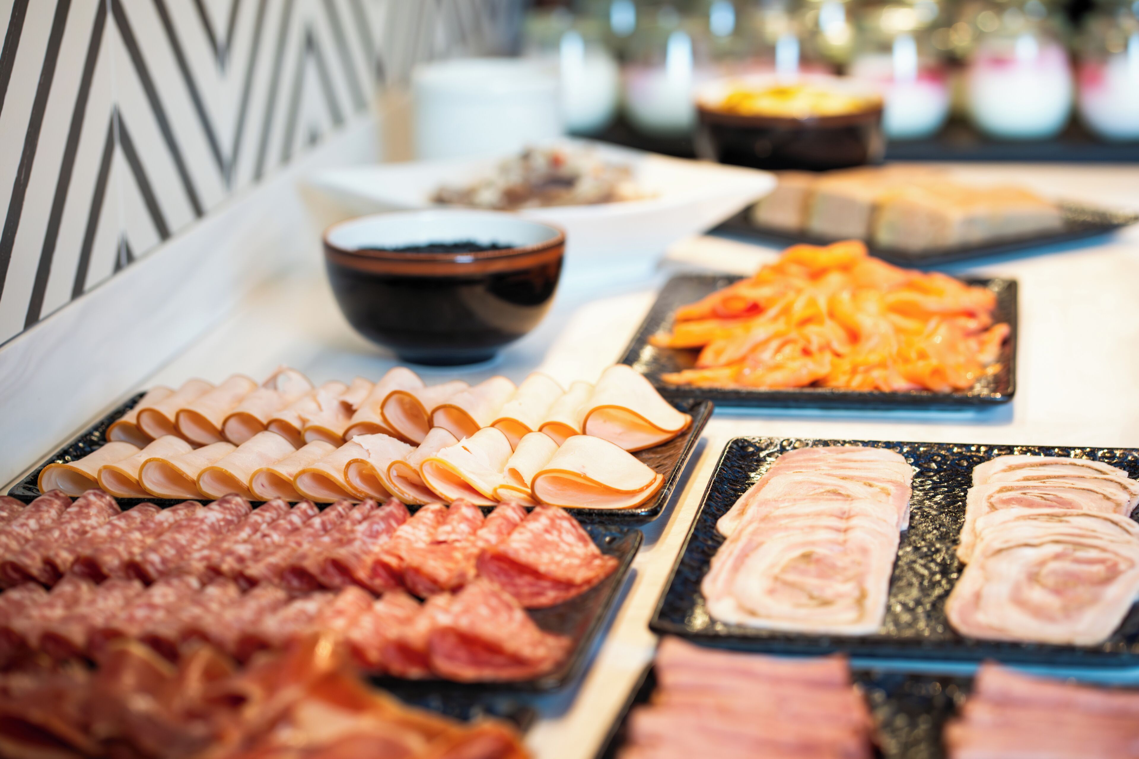 A buffet with various meats and cheeses.