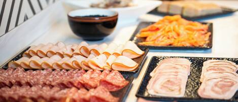 A buffet with various meats and cheeses.