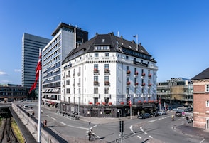 A historic building with multiple floors, a prominent corner location, and a flagpole with a flag.