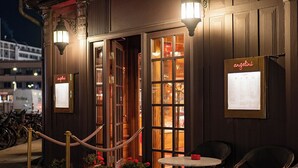 Un restaurante con alfombra roja, mesas al aire libre y plantas en macetas.