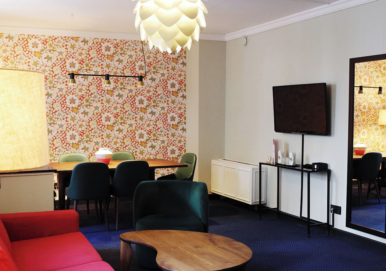 Ein modernes Wohnzimmer mit einem roten Sofa, einem Holztisch und einem Essbereich mit Tisch und Stühlen.